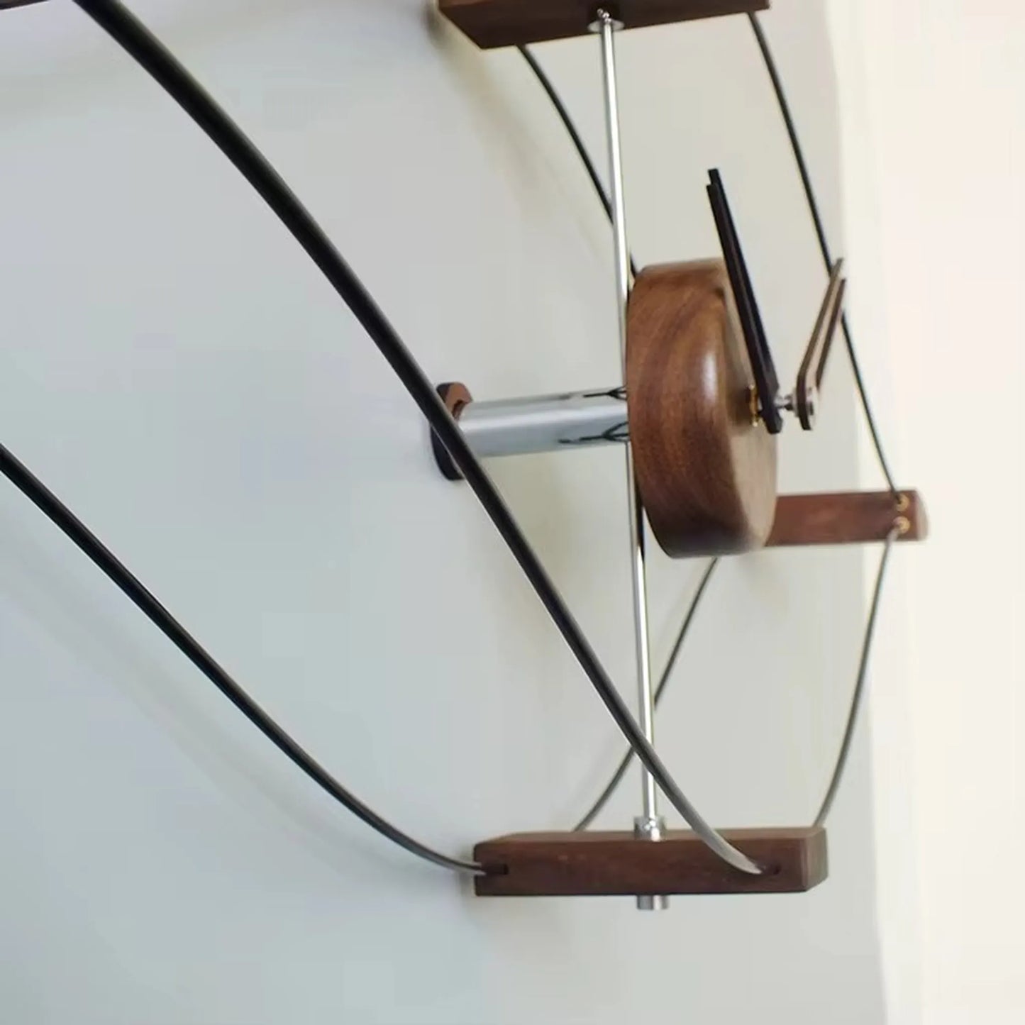 Modern metal wall clock detail showing slim hour and minute hands