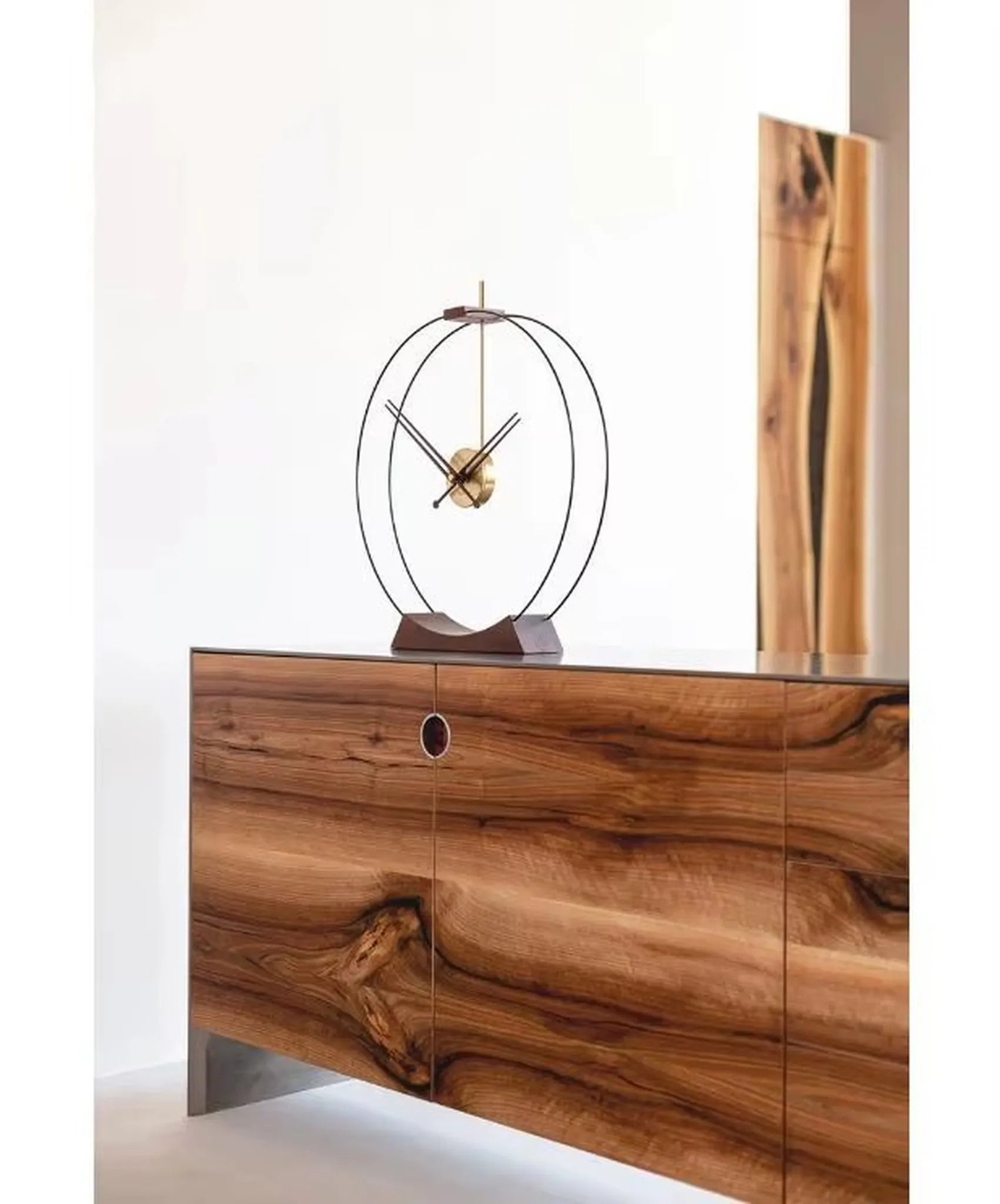 Design table clock - Bexley: A minimalist clock with two black metal rings and brass movement, set on a wooden base, showcased on a wooden sideboard, embodying sophisticated, contemporary design.