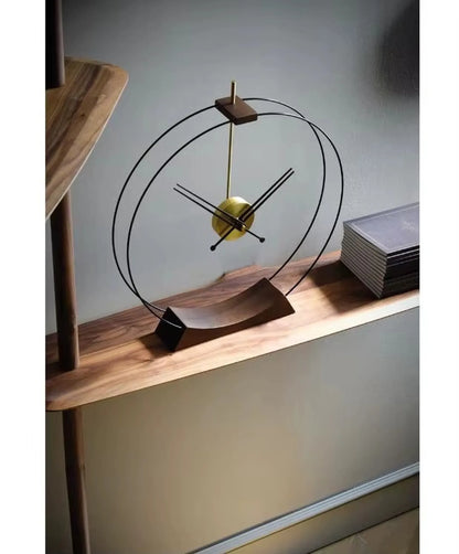Design table clock - Bexley: A minimalist clock on a wooden console, featuring a slender post with black metal rings and a brass clock movement, next to a stack of books for a modern aesthetic.