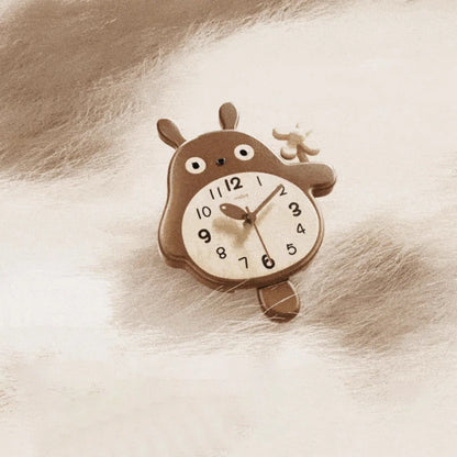 Small decorative wall clocks - Veynor A charming analog clock designed as a chubby cartoon animal with big eyes and a belly clock face, resting on a soft, plush surface.