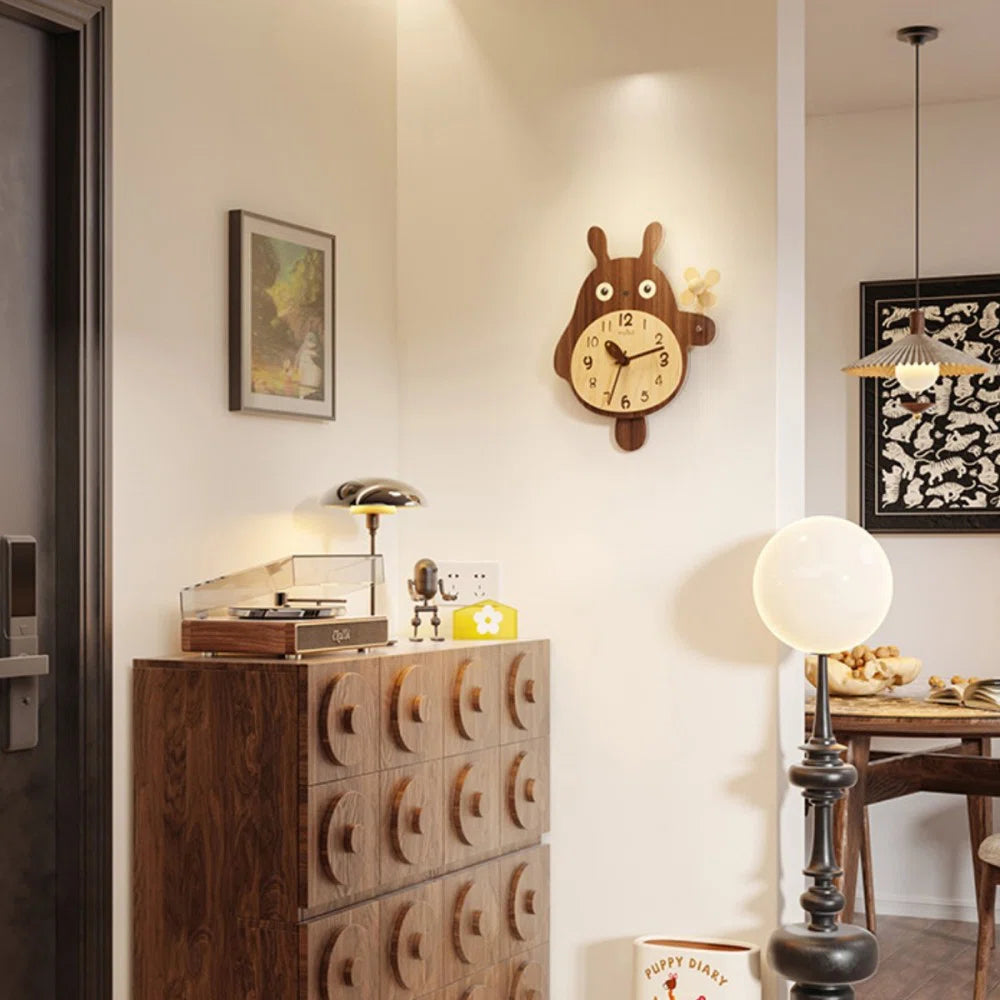 Small decorative wall clock - Veynor, resembling a cartoon bunny with big eyes, hangs above a dark wood chest, adding playful charm to a cozy mid-century interior corner.