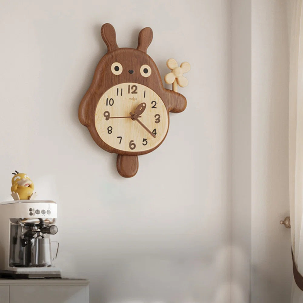 Veynor wall clock, a whimsical wooden bear-bunny hybrid with a pendulum tail, adds charm above a coffee machine topped with a yellow figurine, enhancing your space with natural beauty.