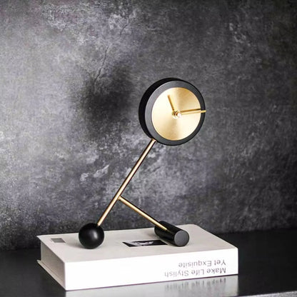 Metal Tabletop Clock - Winsley: A modern clock with a round gold face, black rim, and decorative gears, supported by slender gold rods, adding industrial charm to any desk or mantel.