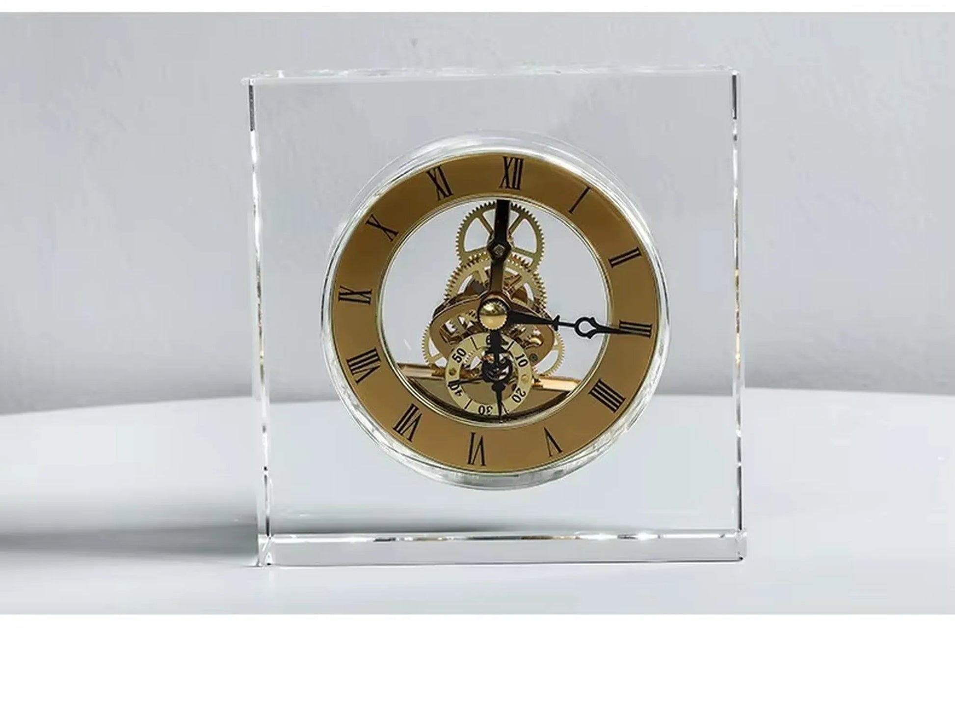 Crystal tabletop clock - Dunley: A small, clear-block clock with a gold-tone skeleton movement, featuring visible brass gears and Roman numerals, elegantly framed in beveled glass, ideal for modern decor.