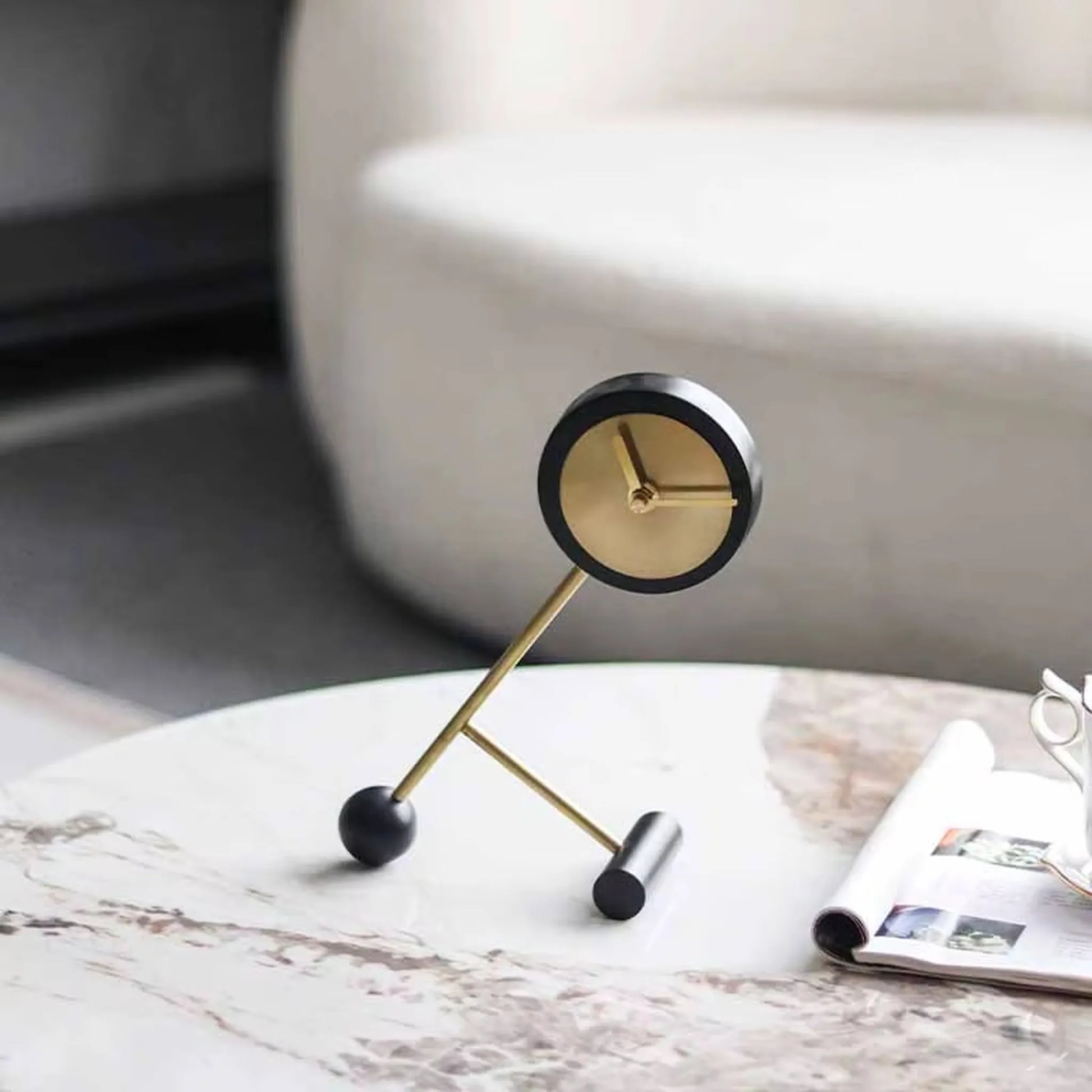Metal Tabletop Clock - Winsley: A minimalist clock with a brass face and decorative gears, set on a marble-patterned table, supported by abstract brass rods, embodying industrial charm.