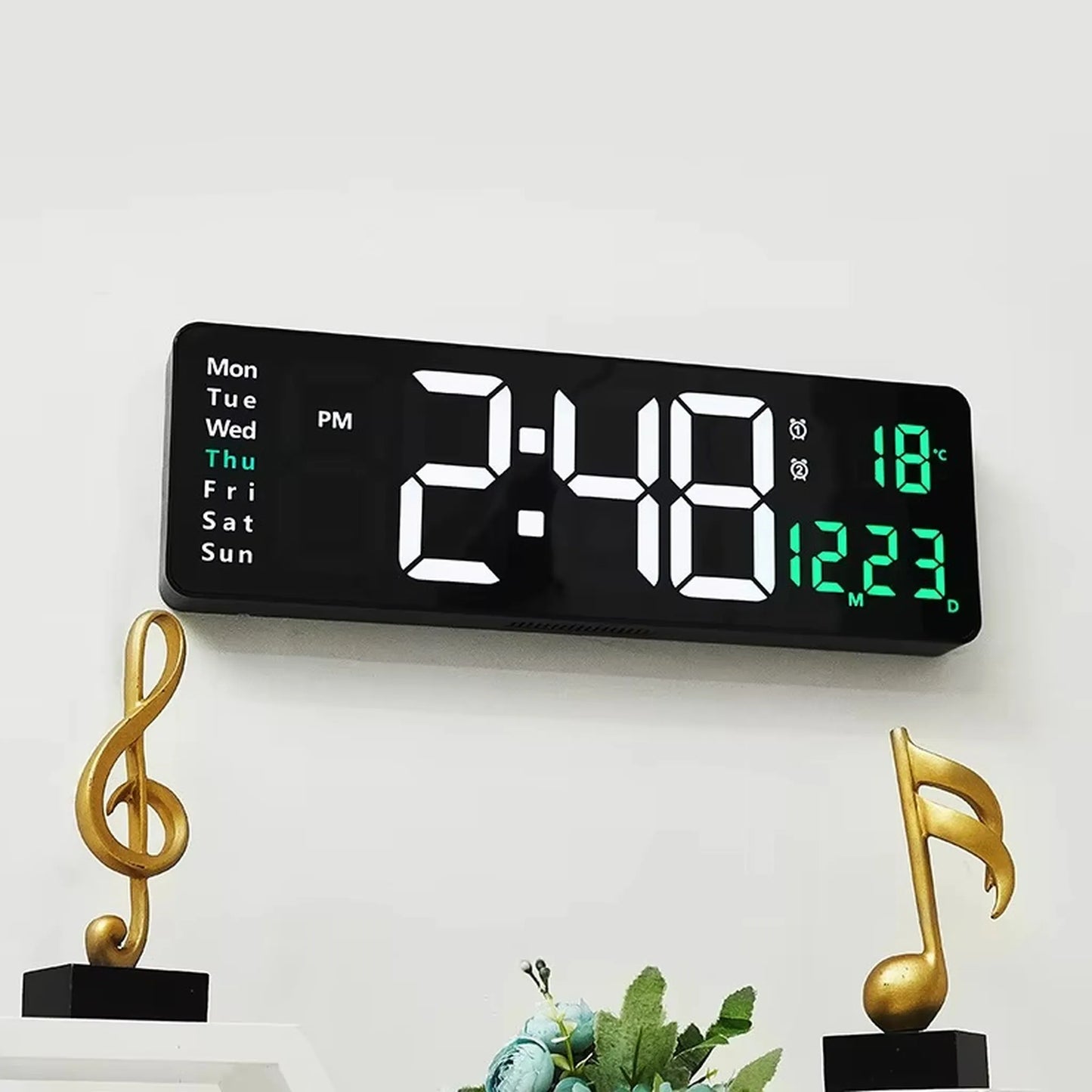Large digital wall clock - Eldon with bold LED display showing 2:48 PM, Thu, temperature 18 °C, and date 12 23, mounted above a shelf with golden music-note sculptures.
