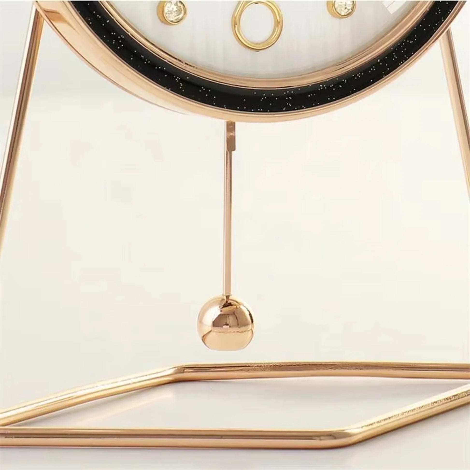 Pendulum Table Clock - Dralen: A gold-tone metal desktop piece with a minimalist circular frame, featuring a black starry rim and a swinging brass pendulum, blending classic style with modern elegance.