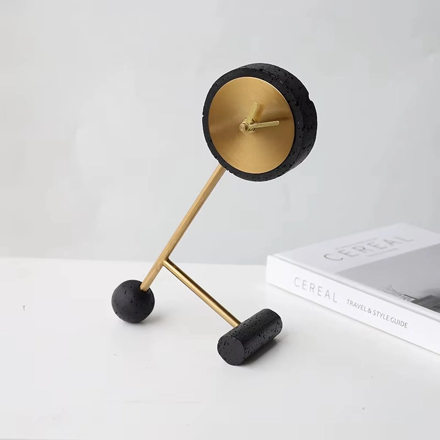 Metal Tabletop Clock - Winsley: A sculptural clock featuring a gold face within a textured black frame, mounted on angular gold rods. Ideal for adding industrial charm to desks or mantels.