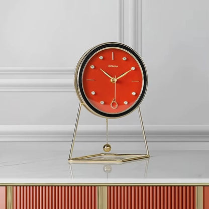 Pendulum Table Clock - Dralen: A modern tabletop clock with a red dial, gold accents, and a swinging pendulum, elegantly supported by a gold-wire stand, perfect for mantel or desk display.
