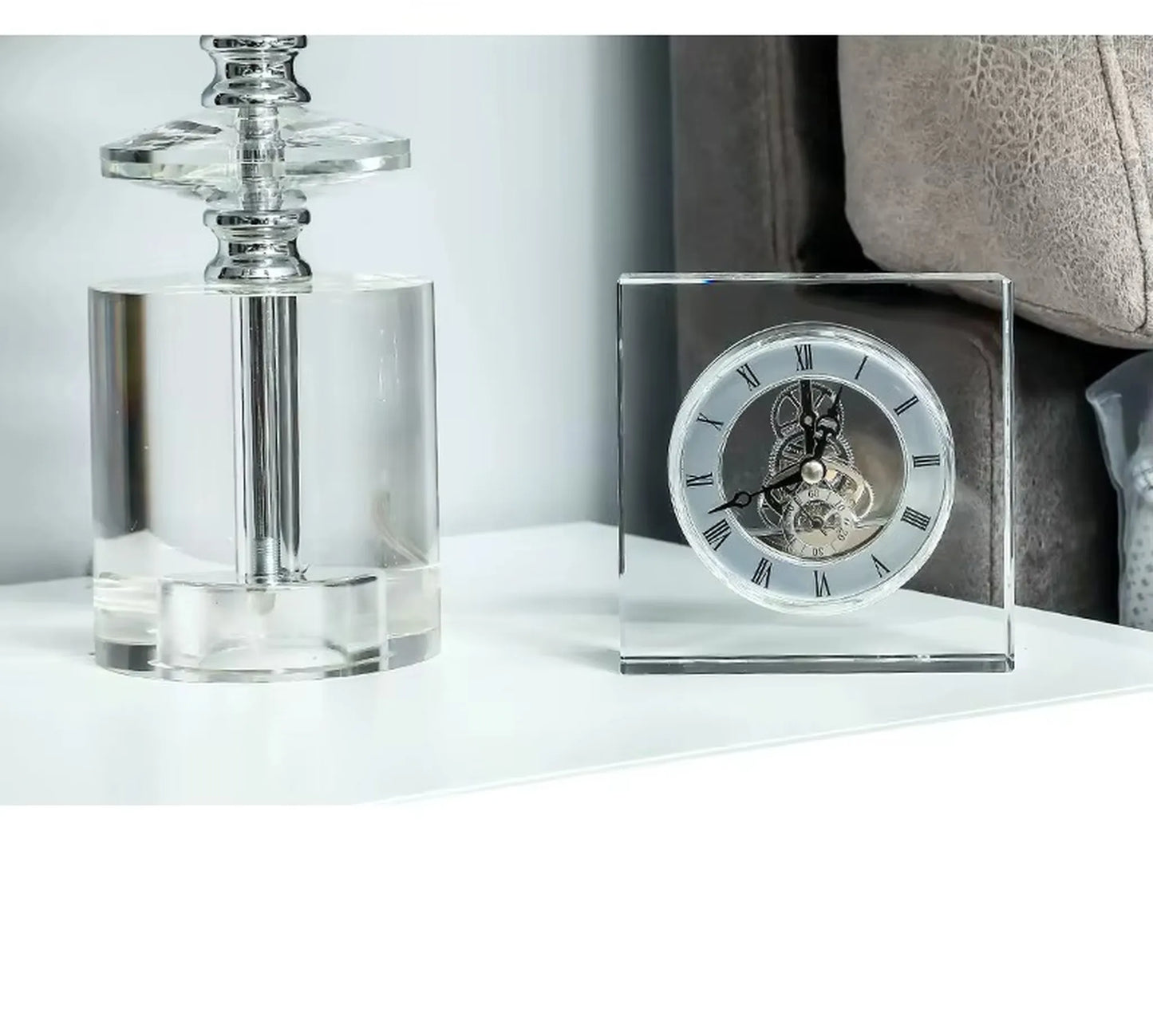 Crystal tabletop clock - Dunley: A clear-acrylic square clock showcasing exposed gears and Roman numerals, elegantly enhancing a minimalist white tabletop alongside a transparent acrylic lamp base.