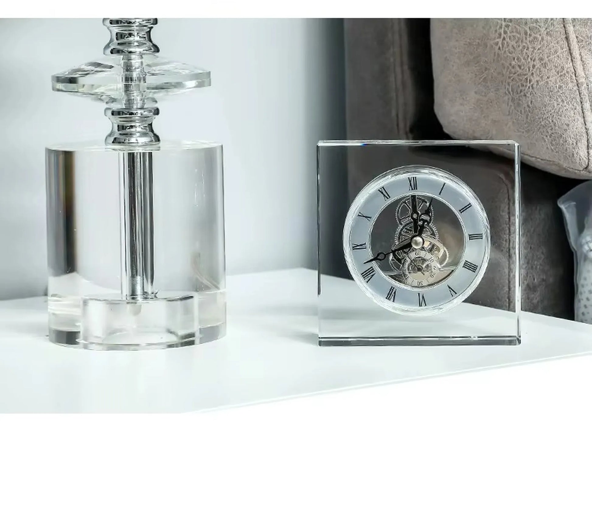 Crystal tabletop clock - Dunley: A clear-acrylic square clock showcasing exposed gears and Roman numerals, elegantly enhancing a minimalist white tabletop alongside a transparent acrylic lamp base.