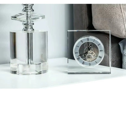 Crystal tabletop clock - Dunley: A clear-acrylic square clock showcasing exposed gears and Roman numerals, elegantly enhancing a minimalist white tabletop alongside a transparent acrylic lamp base.
