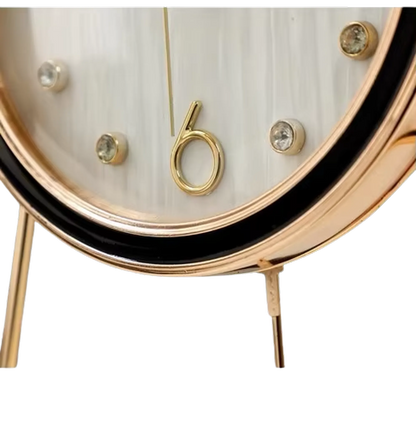 Pendulum Table Clock - Dralen: A close-up of this elegant clock features a gold-tone bezel and legs, white face with crystal markers, and a stylized gold “6” at the bottom.
