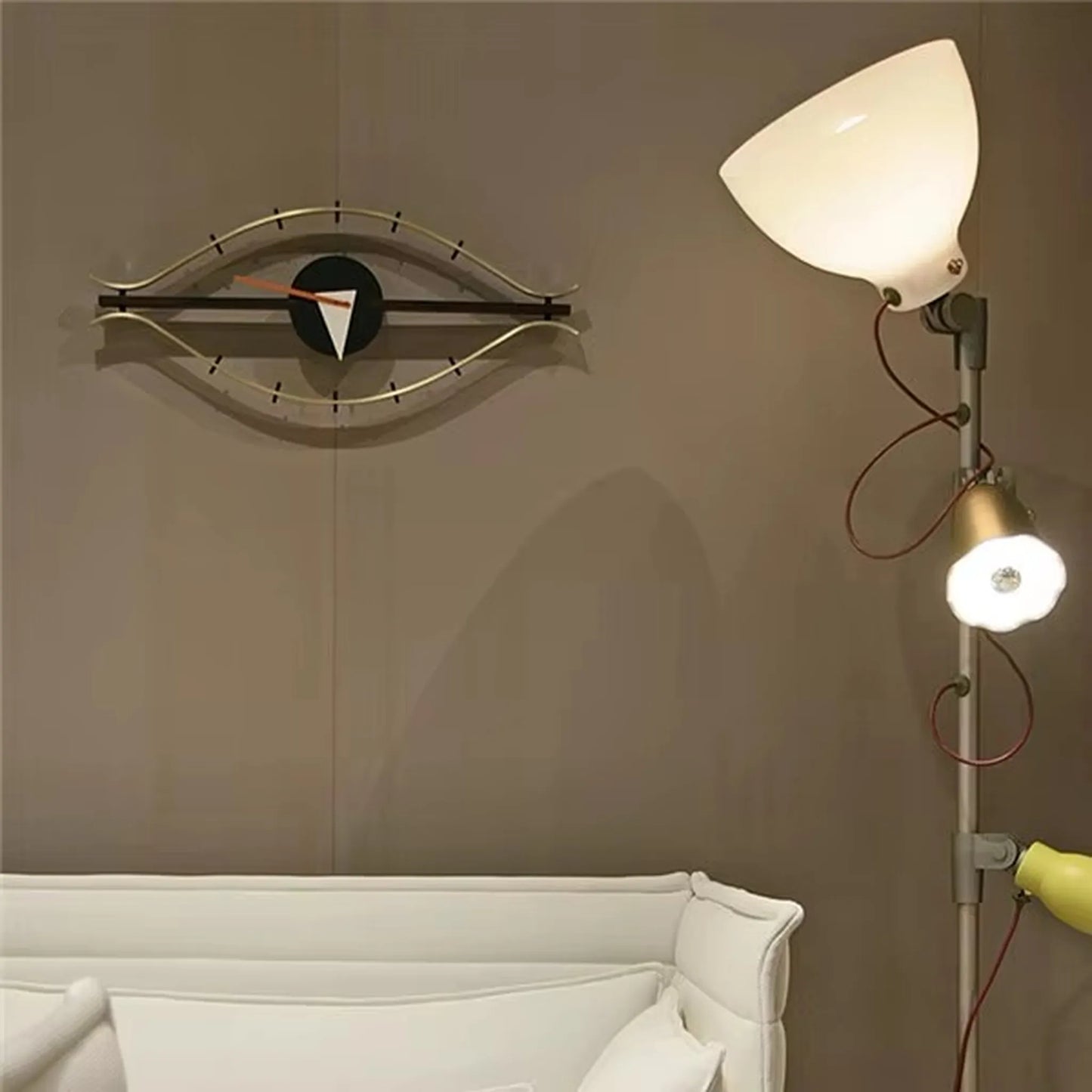 30-inch decorative wall clock - Ashen: Eye-shaped with minimalist markers and curved metal rails, mounted on a taupe wall. This sculptural clock adds industrial vintage charm to any space.