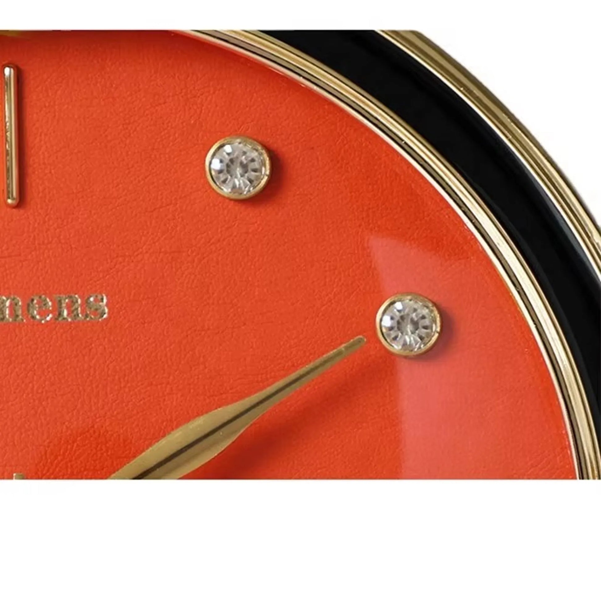 Pendulum Table Clock - Dralen: Close-up of a vibrant orange wristwatch-style dial with gold and crystal hour markers, reflecting the clock's dynamic elegance and unique, open-concept design for desks or mantels.