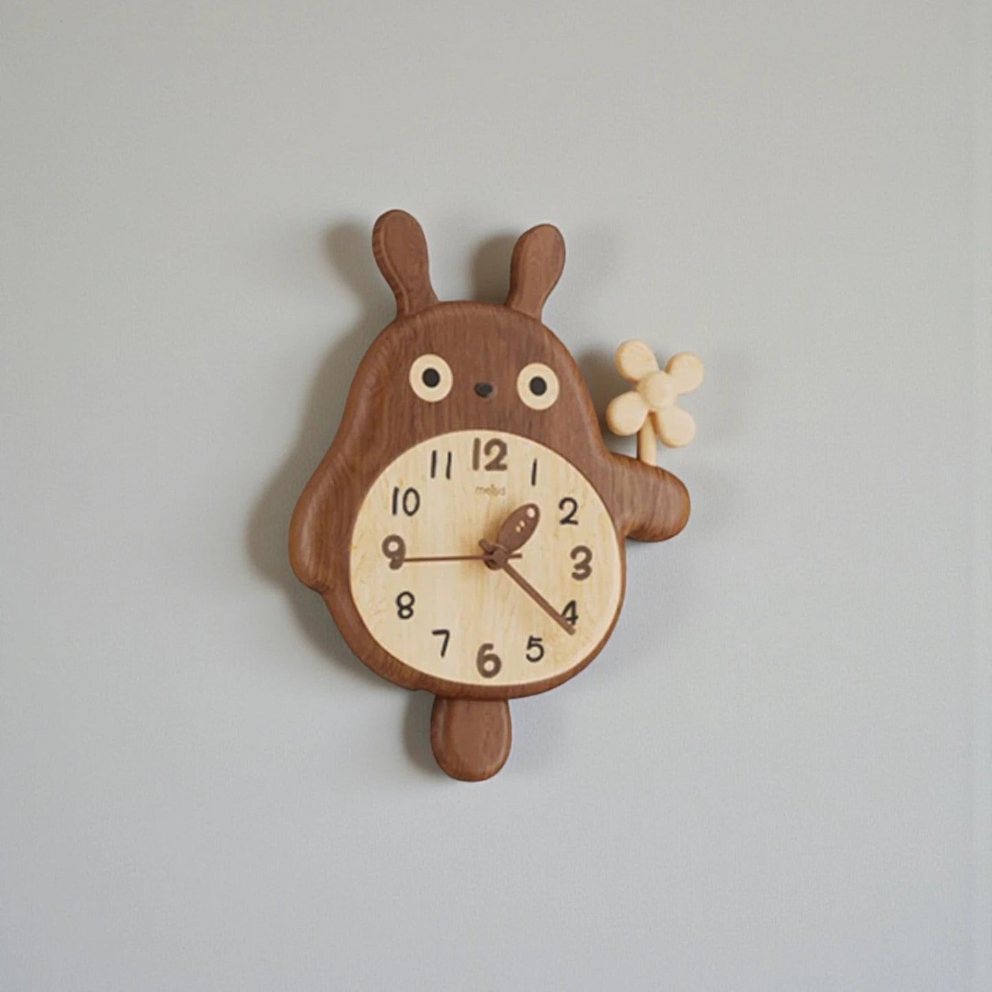 Small decorative wall clocks - Veynor: A wooden wall clock shaped like a cartoon animal with a clock face on its belly, holding a flower in its paw, featuring a tail pendulum below.