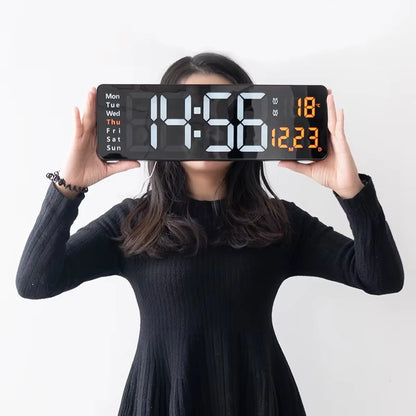 Person holding Large digital wall clock - Eldon displaying 14:56, Thursday, and 18°C. Ideal for spacious settings with its jumbo LED numerals and included remote control.