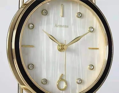 Pendulum Table Clock - Leiton features a gold-tone bezel and hands, pearlescent white dial, crystal markers, and a rhythmic pendulum, embodying elegance and artistic motion for mantel or desk display.