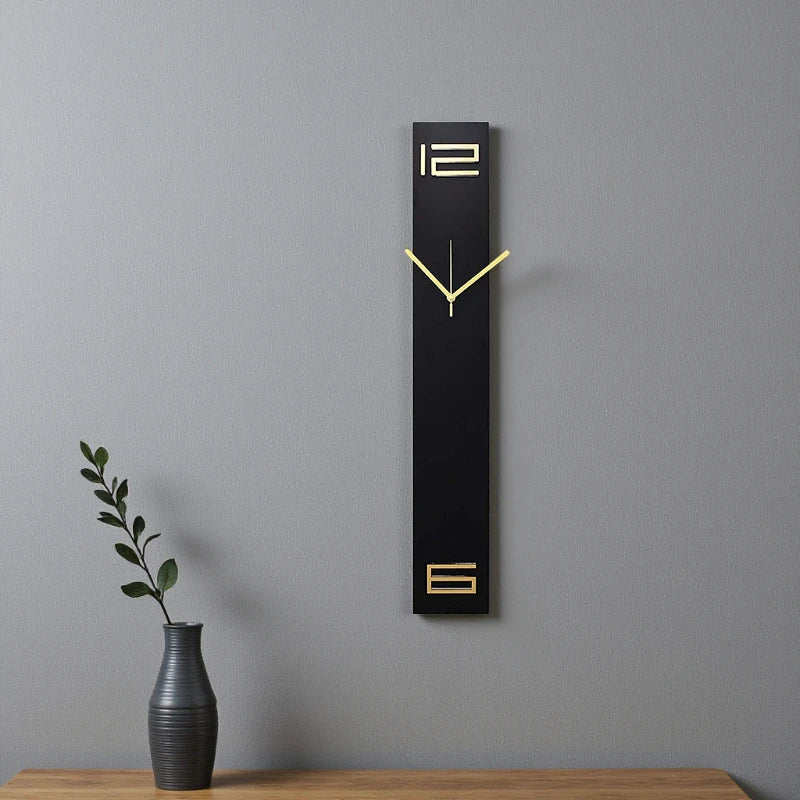 Modern long wall clocks - Rowell: A sleek black clock with gold hands, featuring 12 and 6 numerals, elegantly adorns a light gray wall above a wooden shelf, complemented by a dark-grey vase with a leafy branch.