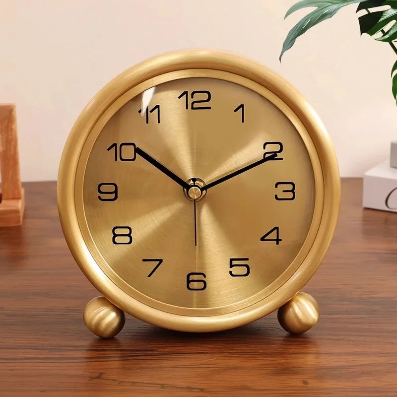 Brass Table Clock - Helric: A small, round, brass-colored tabletop clock with black numerals and hands, set on spherical feet, elegantly complements desks or mantels with its timeless design.