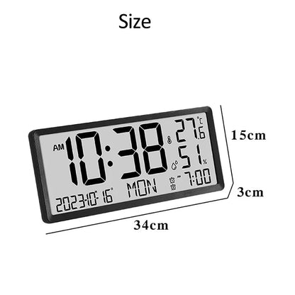 White Digital Clock - Carradon: Black-framed rectangular clock featuring a large LCD display showing current time, temperature, humidity, date, day, and alarm time. Dimensions: 34 cm wide × 15 cm tall × 3 cm thick.