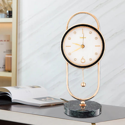 The Leiton Pendulum Table Clock features a minimalist face with gold accents and a pendulum, set in an elegant gold frame on a dark marble base, ideal for modern decor.
