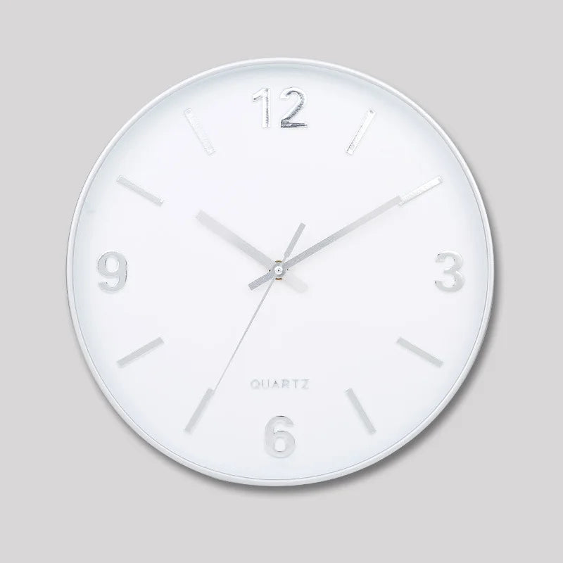Modern Silent Wall Clock - Densford with a white face, silver hands, and raised metallic numerals at 12, 3, 6, and 9. Features a silent, non-ticking quartz movement for contemporary elegance.