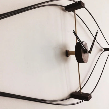 Black metal wire frame clock showing curved diamond geometric design