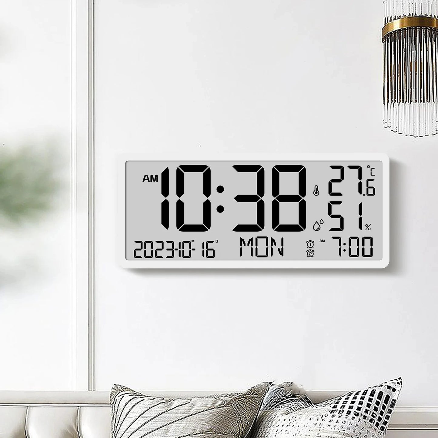 White Digital Clock - Carradon mounted on a minimalist wall, displaying time, date, temperature, humidity, and alarm settings. Positioned above a sofa with cushions, capturing modern design simplicity.
