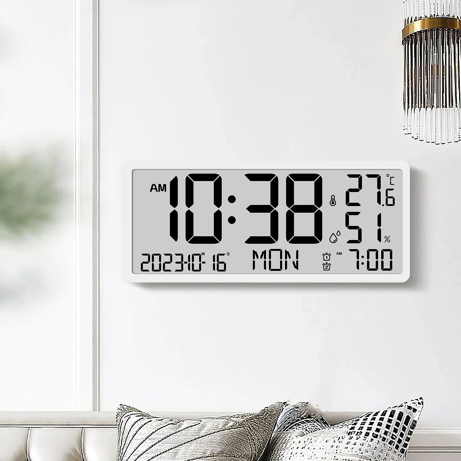 White Digital Clock - Carradon mounted on a minimalist wall, displaying time, date, temperature, humidity, and alarm settings. Positioned above a sofa with cushions, capturing modern design simplicity.