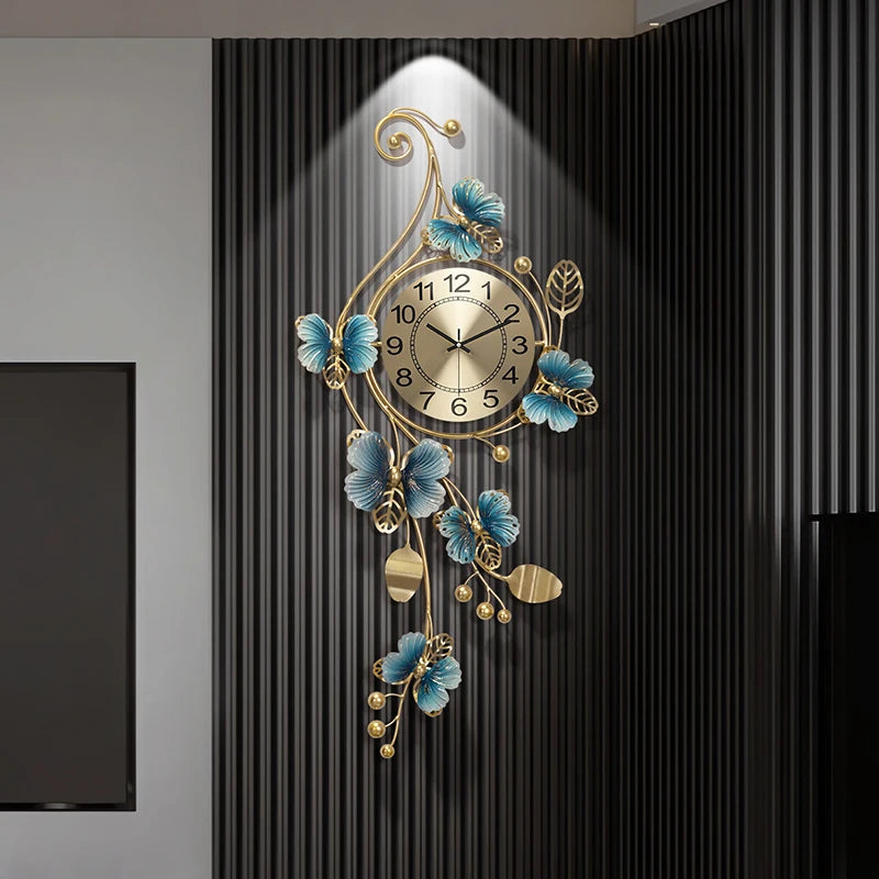Hanging Wall Clock - Elmsford features a gold-toned face with black numerals, surrounded by vine-like metalwork with blue flowers and gold leaves, set against a dark ribbed panel.