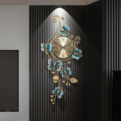 Hanging Wall Clock - Elmsford features a gold-toned face with black numerals, surrounded by vine-like metalwork with blue flowers and gold leaves, set against a dark ribbed panel.