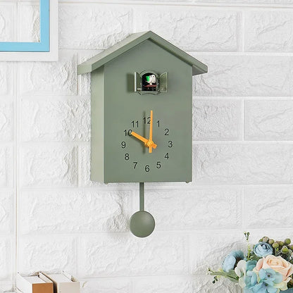 Wooden Cuckoo Clock - Brivon: A minimalist, house-shaped wall clock with bright yellow hands and a swinging bird pendulum, mounted on a white brick wall with open cuckoo doors.