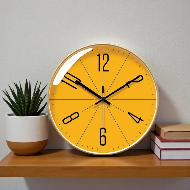 Nordic wall clock - Branley, featuring a yellow face with black hands and numerals, leans stylishly on a wood shelf, complemented by a succulent and books, embodying minimalist, Nordic design.