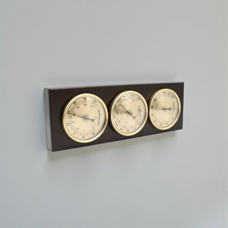 Weather Station Wall Clock - Harlton: A wall-mounted, elegant brass-finished panel featuring a thermometer, barometer, and hygrometer set into a dark wooden plaque, ideal for monitoring indoor conditions.