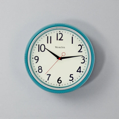 Blue metal Wall Clock - Farlton features a round teal frame with a classic analog face, displaying a time of 10:15. This modern clock adds a sleek, silent touch to any space.