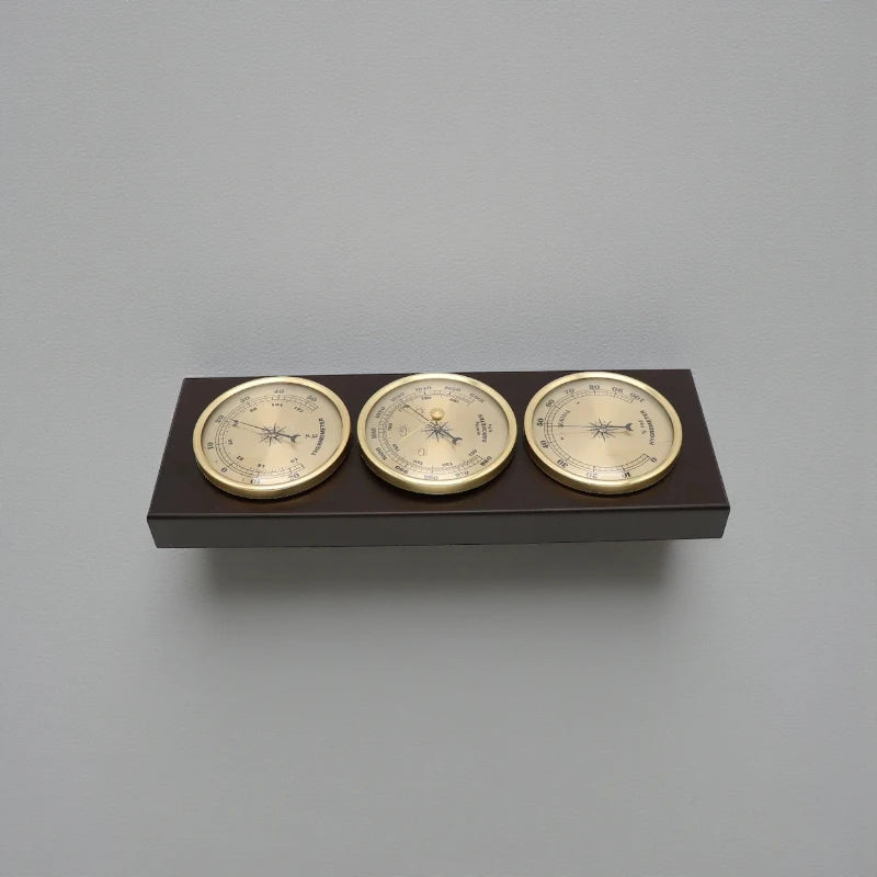 Weather Station Wall Clock - Harlton: A wall-mounted instrument featuring brass-rimmed hygrometer, barometer, and thermometer on a dark wooden plaque, embodying classic elegance from The Horologista's collection.
