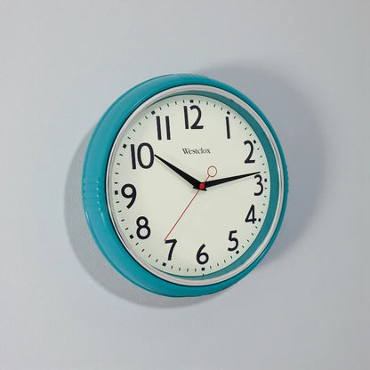 Blue metal Wall Clock - Farlton by Westclox with a teal frame and white face, featuring bold black numerals and hands. The clock shows 10:10 with a red second hand, enhancing any contemporary space.