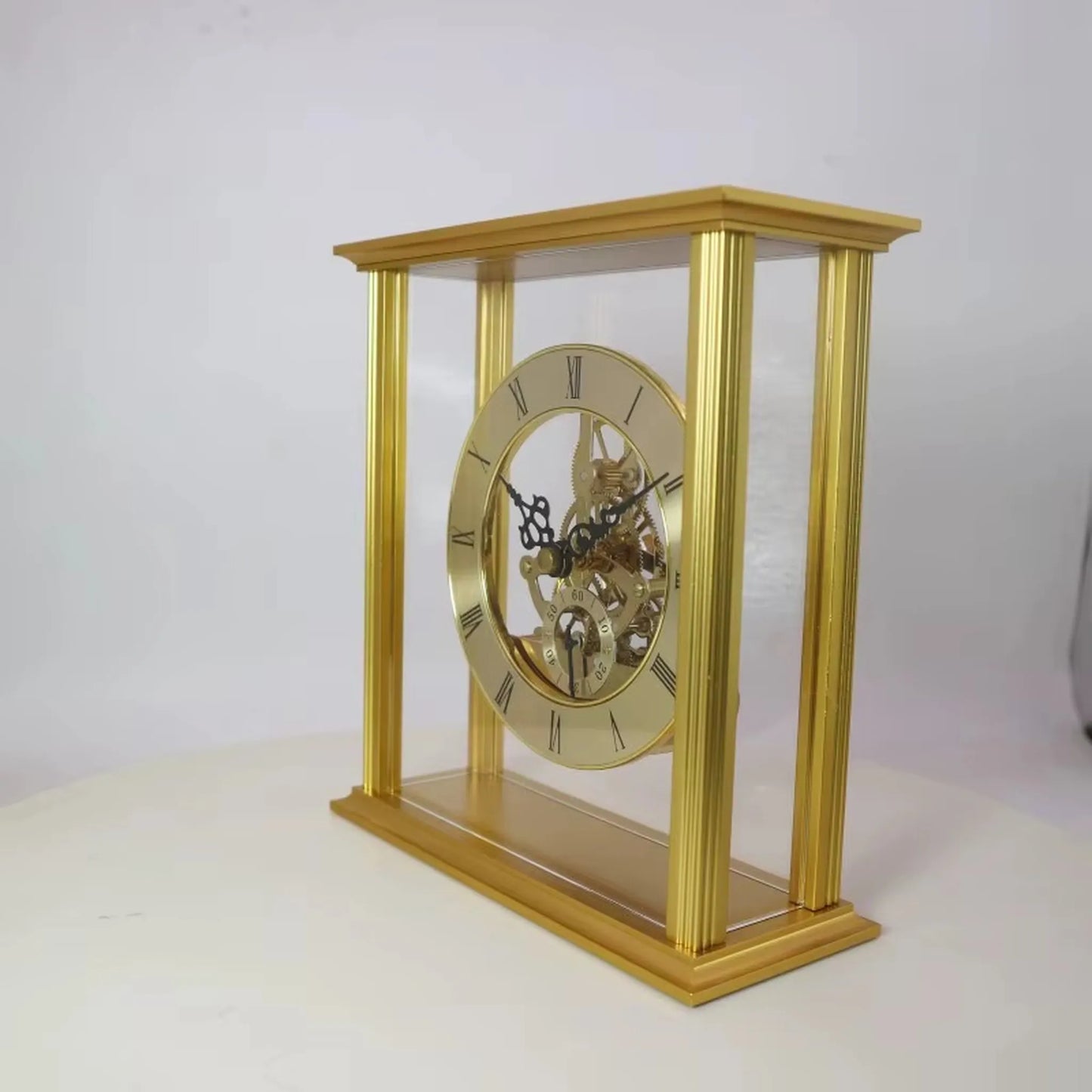 Brass table clock - Braven: A sophisticated mantel clock with a gold frame, glass panels, exposed brass gears, and a Roman numeral face, epitomizing timeless elegance for your desk or mantel.