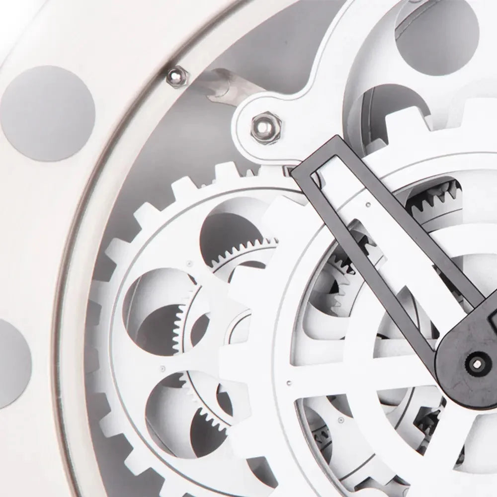 Modern Wall Clock Design - Elverton showcases exposed white gears interlocking beneath a clear cover, with a black hand visible, embodying a skeleton-style aesthetic with bold Roman markers and gun-metal trim.
