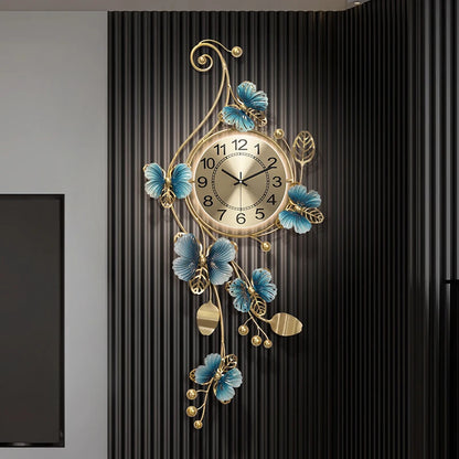 Hanging Wall Clock - Elmsford: A gold-toned round clock with black numerals, surrounded by sculptural metal vines and blue accents, creating an artistic and contemporary wall decor statement.