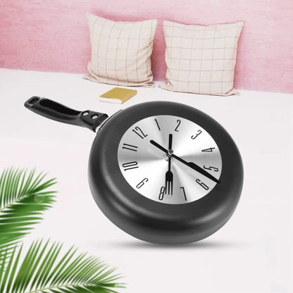 Frying Pan Wall Clock - Ashford: A novelty clock set in a black pan with a brushed-metal face and utensil-shaped hands, adding culinary charm to any kitchen.