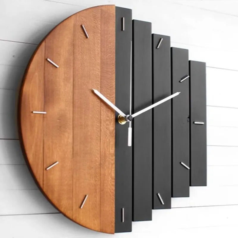 Modern wood wall clock - Clevor made from vertical wooden slats, half natural, half matte black, with metal tick-mark hour indices and minimal silver hands, mounted on a light-colored wall.