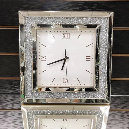 Fancy wall clock - Norwyn features a mirrored frame with crushed glass accents, a white face with minimalist hour markers, and Roman numerals, embodying elegance and serving as a striking room centerpiece.