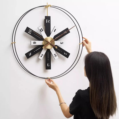 Modern Lounge Wall Clocks - Fremton features a striking brass-centered design with black-and-white rectangular blades, adjusted by a person on a white wall, embodying minimalist elegance and precise timekeeping.