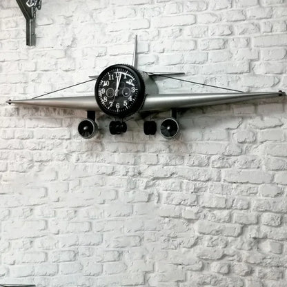 Close-up of airplane clock's black dial face with white numerals and detailed engines