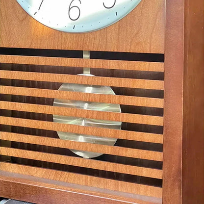 Japanese wall Clock - Lexton, featuring a wooden case with a slatted grill showcasing a swinging metal pendulum bob, and a glimpse of the clock face with numbers 7, 6, and 5.