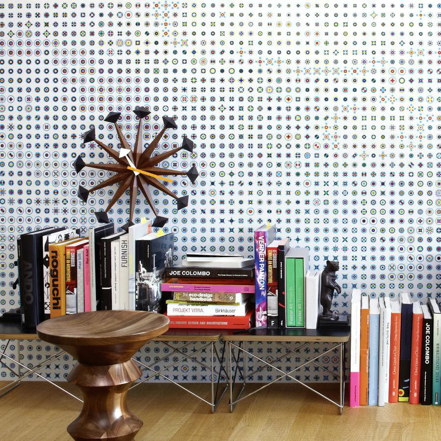 Decorative wall clocks modern - Drayen, featuring a mid-century design with wooden spokes and black tips, prominently displayed above a shelf filled with design books