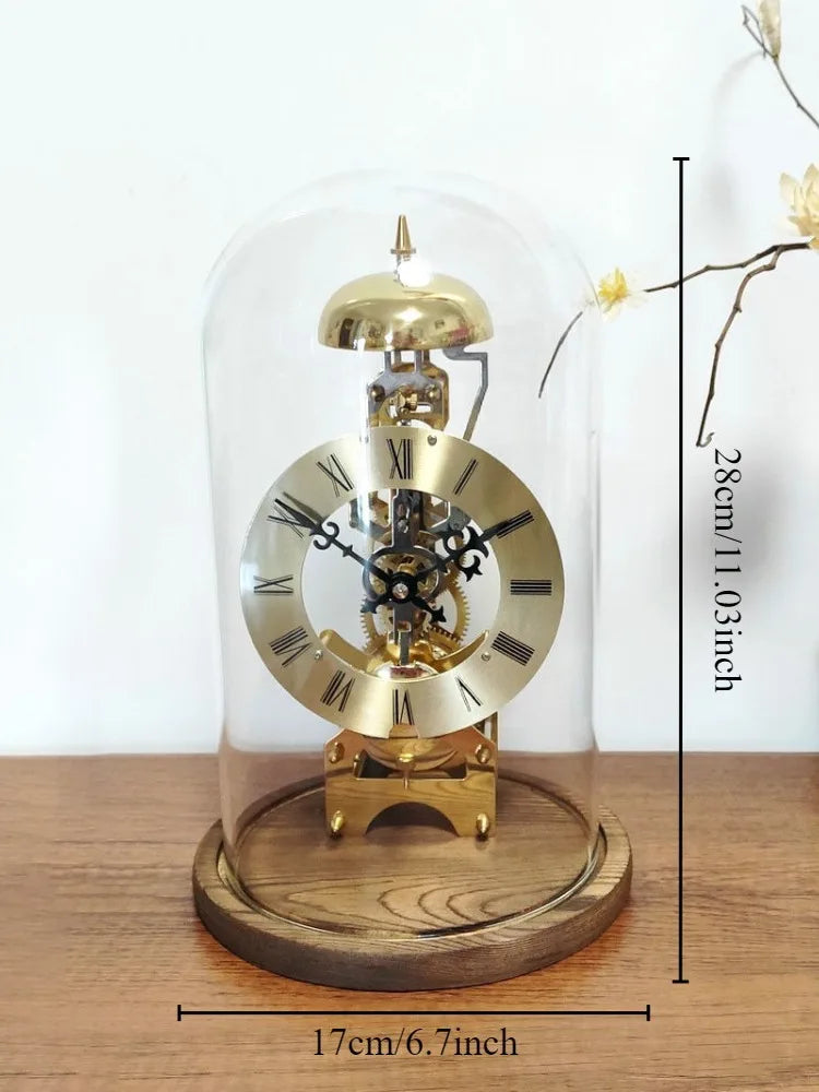 Glass dome clock - Stanley: A brass skeleton mantel clock under glass, showcasing exposed gears, a brass dial with Roman numerals, ornate hands, and a bell, sitting on a wooden base.