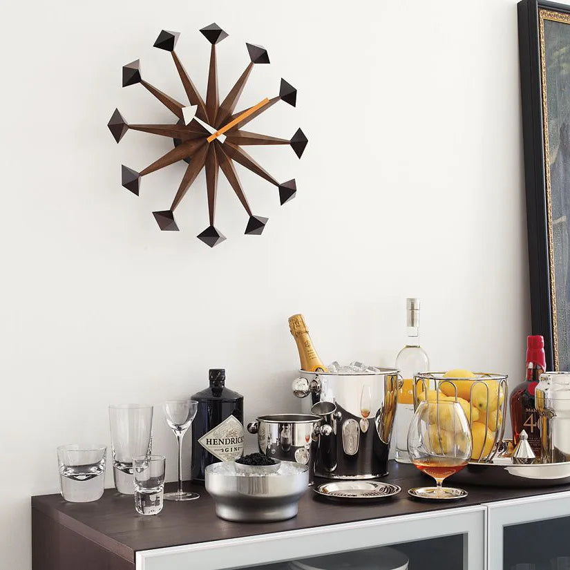 Decorative wall clocks modern - Drayen A mid-century design clock with geometric points, elegantly positioned above a chic home bar setup, embodying retro-modern style. 